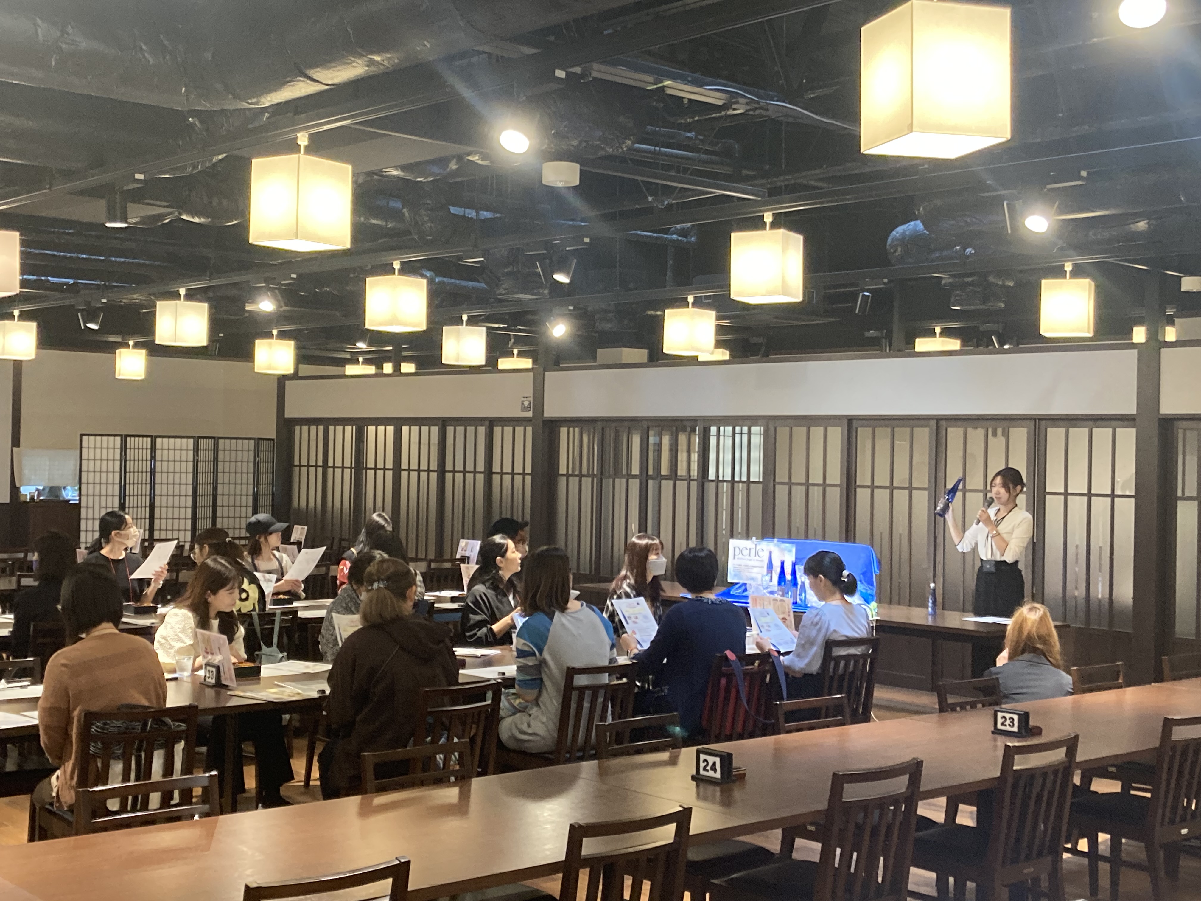 イベント当日の様子。蔵の中に併設されたレストラン会場において、黄桜の担当者による「黄桜 ペルル 特別純米酒」「黄桜 ペルルスパークリング」について商品紹介プレゼンテーションと試飲をする人々の様子。